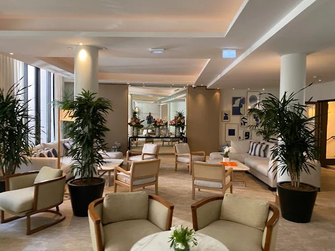 Lobby lumineux du Five Seas avec fauteuils en bois clair et plantes tropicales